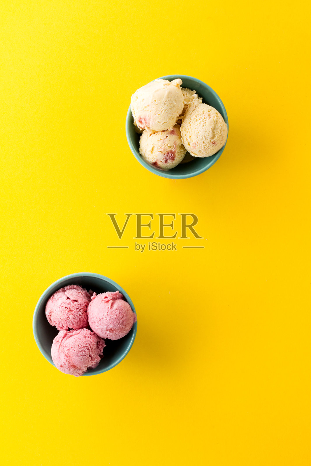 美味的冰淇淋香草草莓勺在蓝色的碗在黄色鲜艳的背景。前视图。照片摄影图片