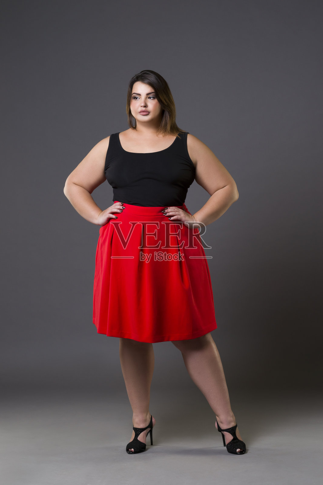 加码时装模特在红色裙子，肥胖的女人在灰色的背景，超重的女性身体照片摄影图片