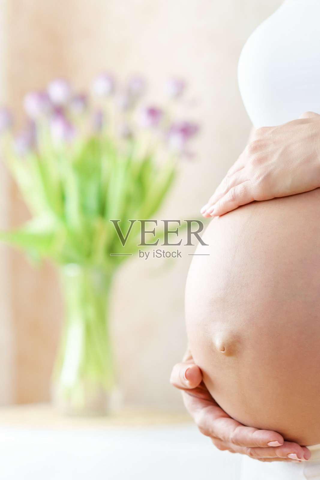 白种孕妇的肚子在明亮的房间和鲜花照片摄影图片