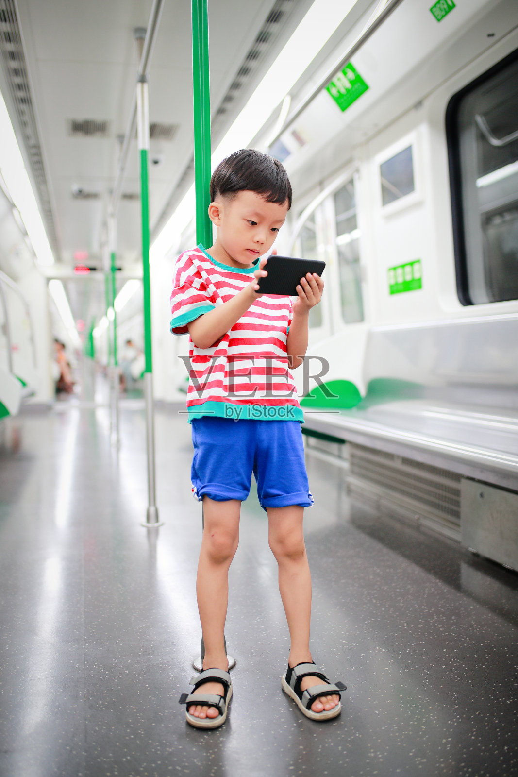 在地铁上用智能手机的男孩照片摄影图片
