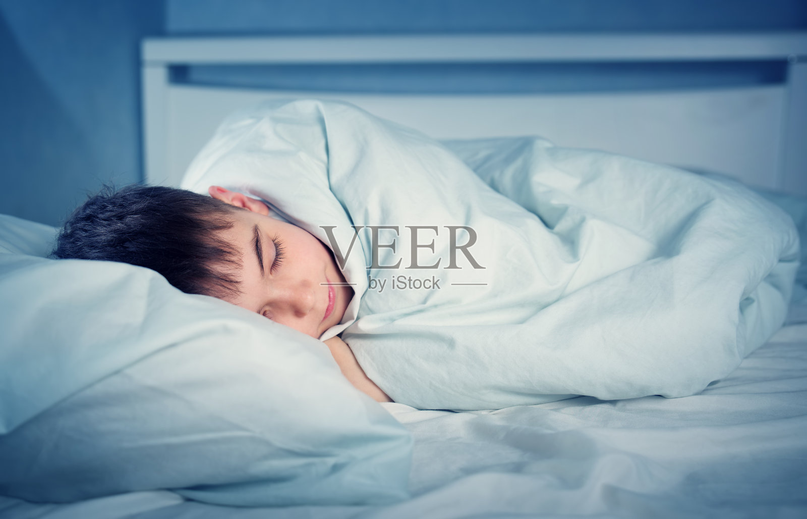 穿着睡衣睡在床上的男孩照片摄影图片