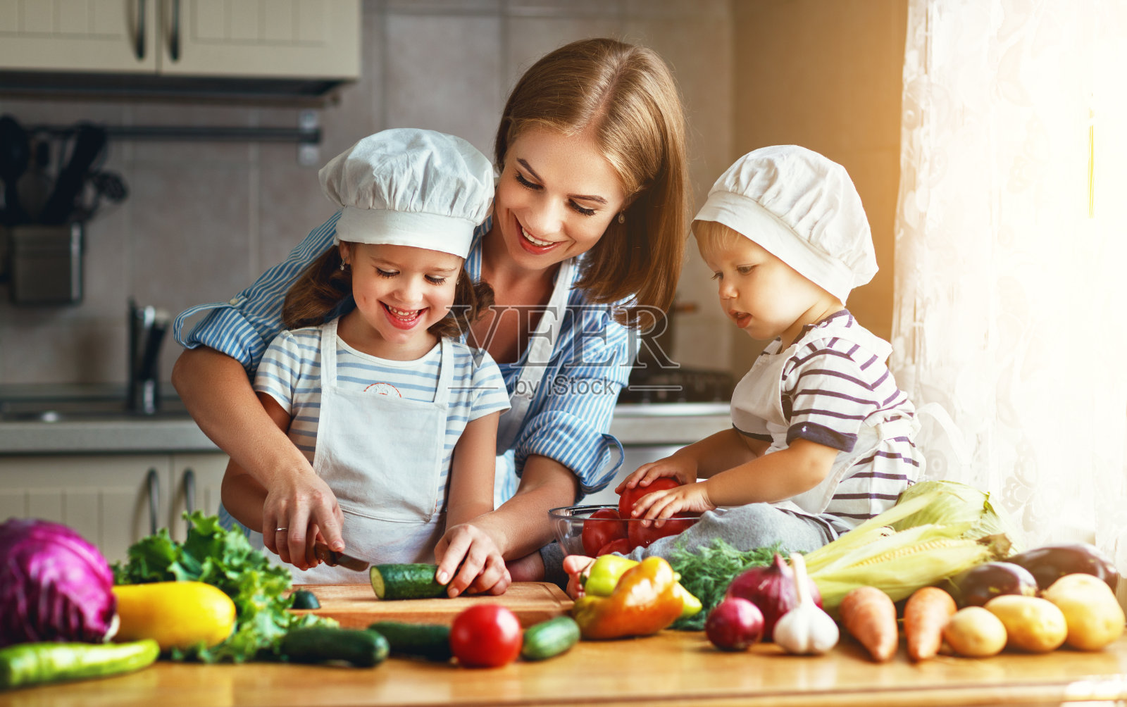 健康饮食。快乐的家庭妈妈和孩子们准备蔬菜沙拉照片摄影图片