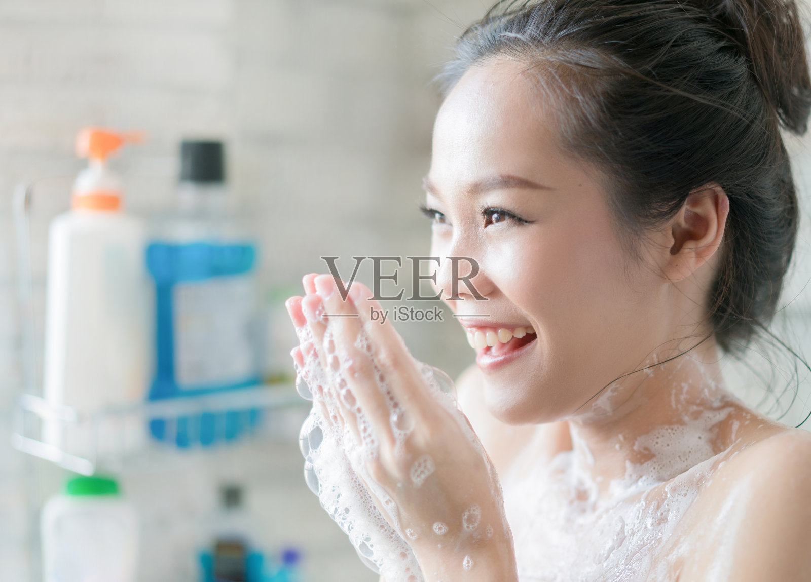 亚洲妇女正在浴室洗澡，她擦肥皂，她是快乐和放松。照片摄影图片
