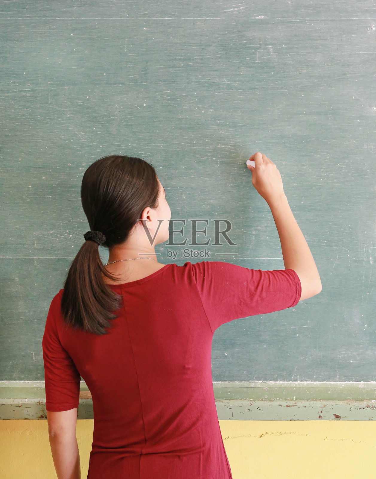 亚洲教师在课堂上用粉笔在黑板上写字，教育理念。照片摄影图片