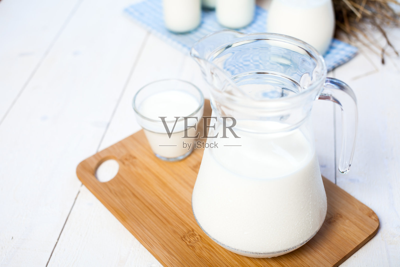 牛奶和几杯牛奶放在一张质朴的木头桌子上。照片摄影图片