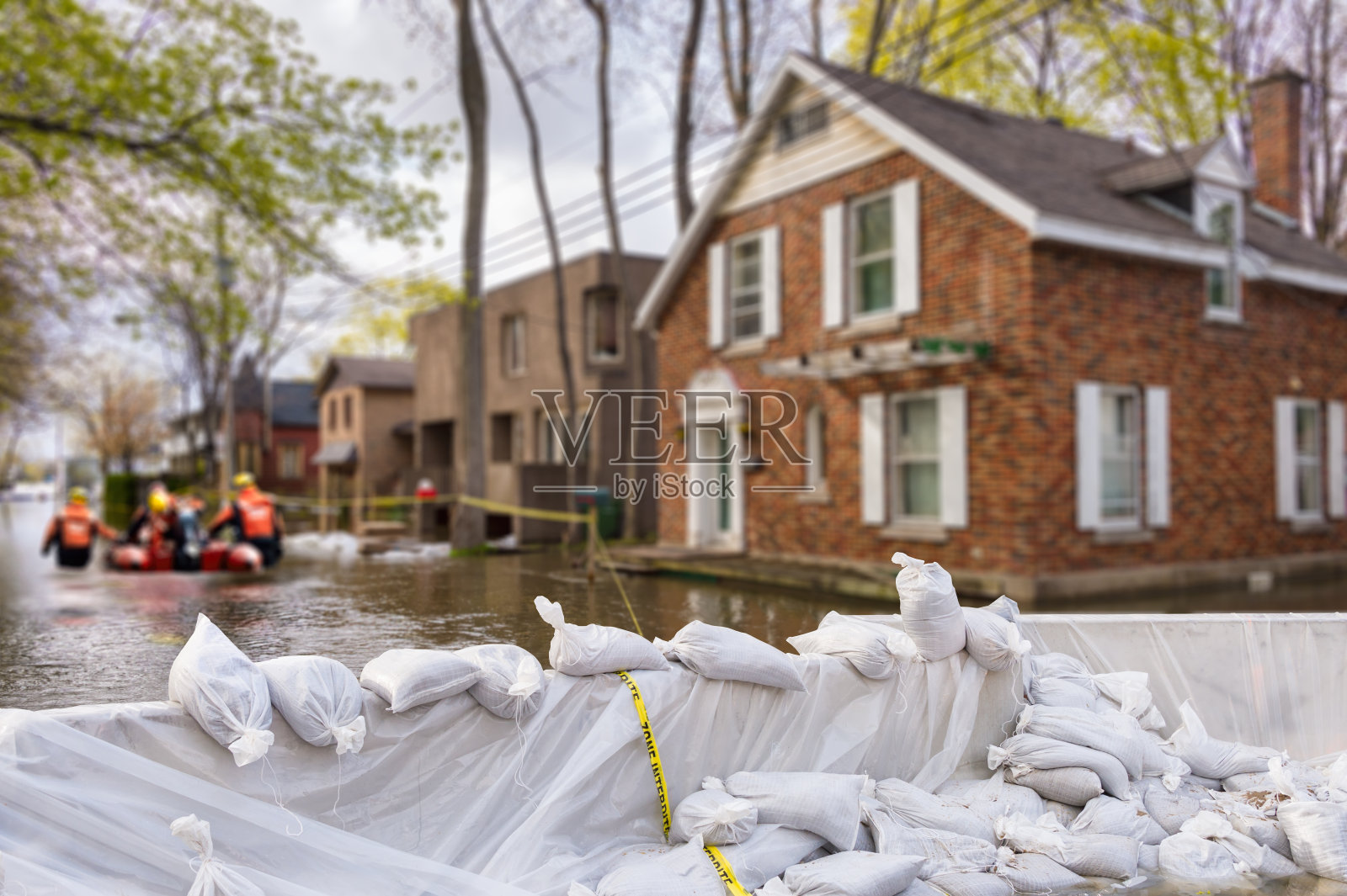 防洪沙袋和被洪水淹没的房屋在背景(蒙太奇)照片摄影图片