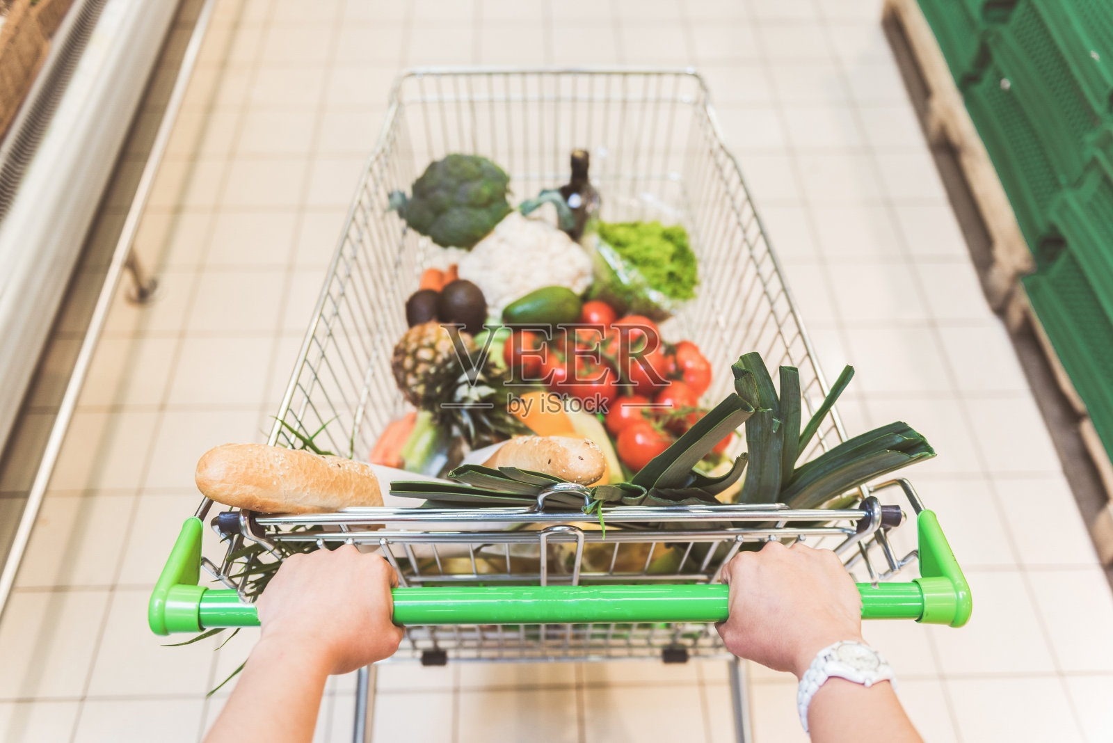女性手臂在超市手推车上放食物照片摄影图片
