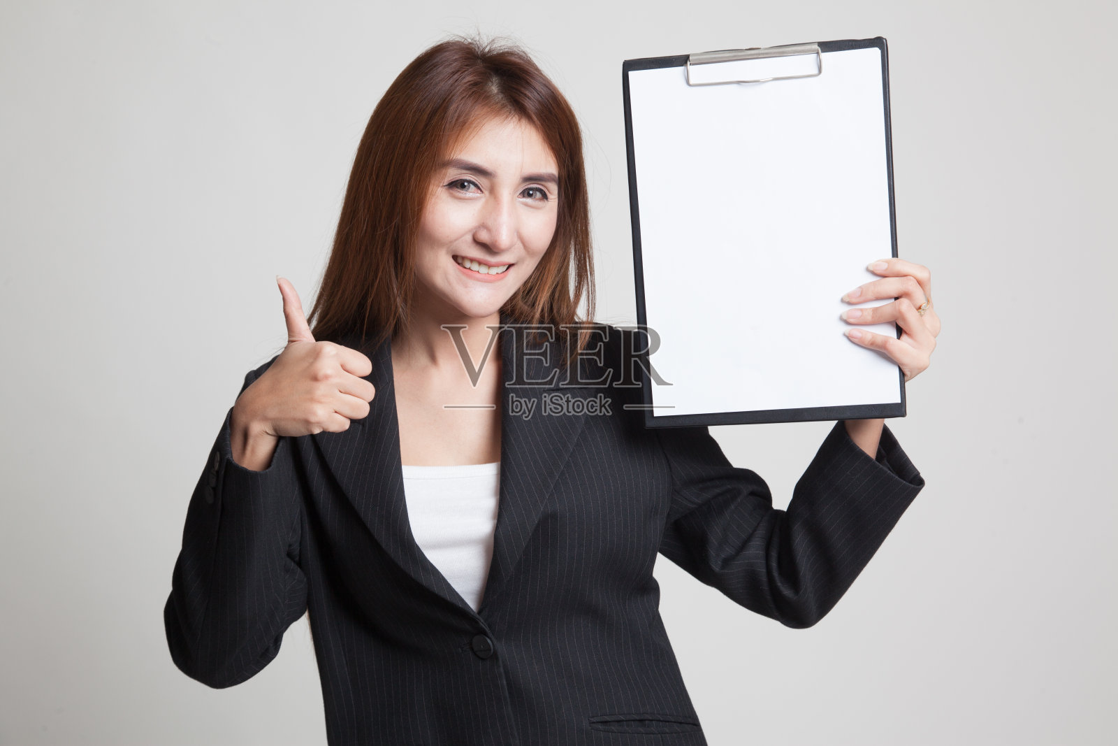 亚洲商业女性显示大拇指和空白的剪贴板。照片摄影图片