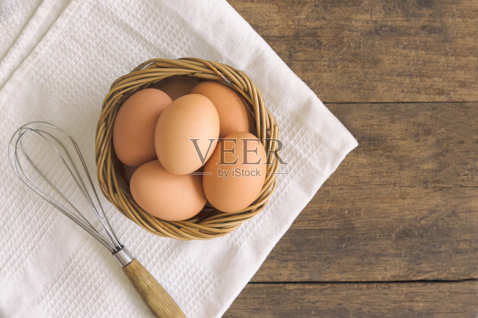 新鲜的鸡蛋放在旧木篮子里，铺上白餐巾。在木桌上准备新鲜的鸡蛋用于烹饪或烘焙。俯视图或平鸡蛋与复制空间的背景或墙纸。照片摄影图片