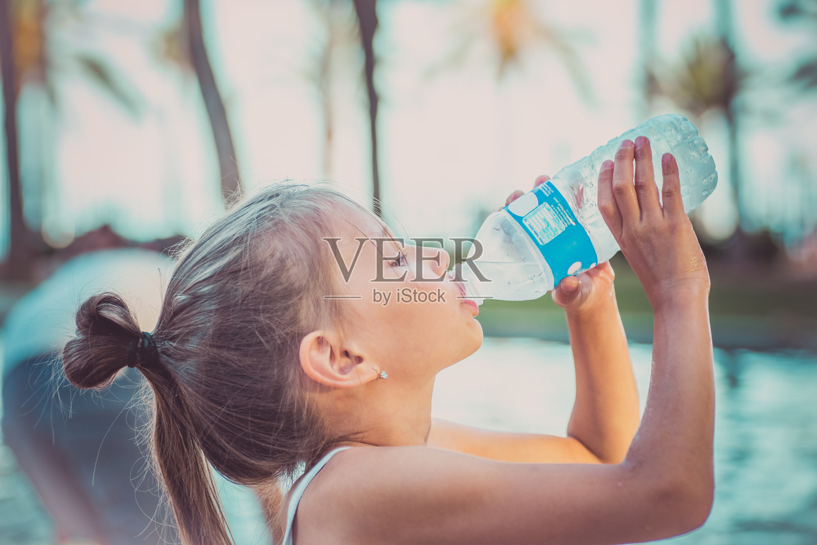 一个孩子正在喝一瓶干净的水。炎热的夏天。照片摄影图片