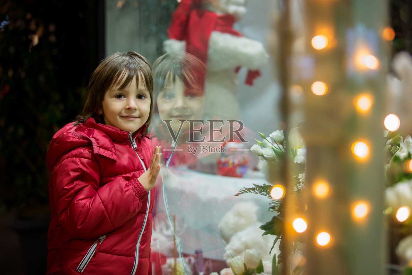 可爱的小孩，男孩，看着商店橱窗里的玩具装饰圣诞节照片摄影图片