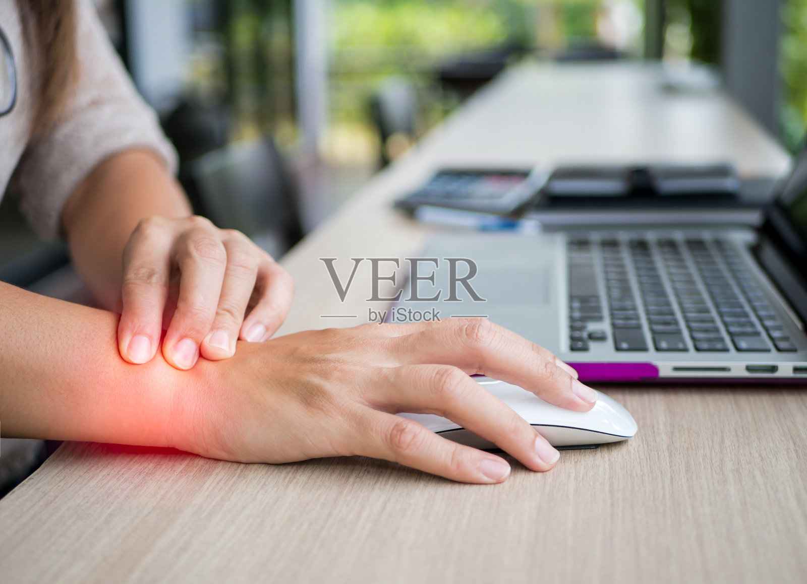 近距离女子持有她的手腕疼痛使用电脑。办公室综合征手痛由职业病所致。照片摄影图片
