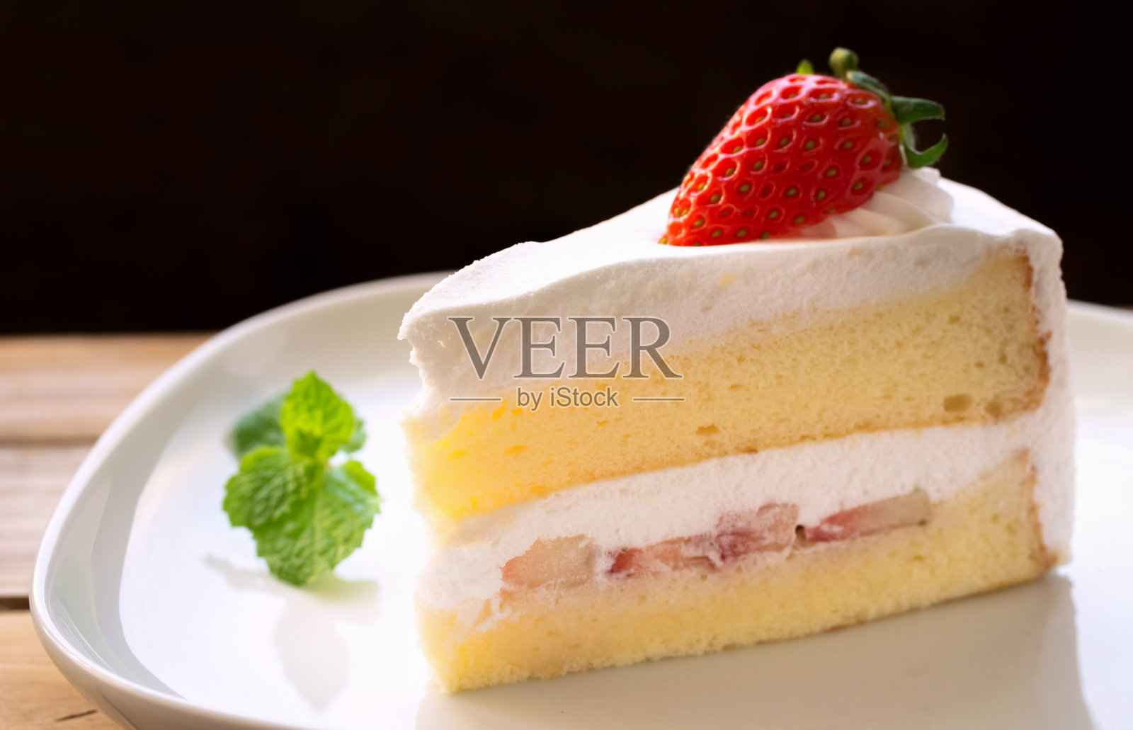 蛋糕与奶油和草莓在一个深色的木头背景。着色。照片摄影图片