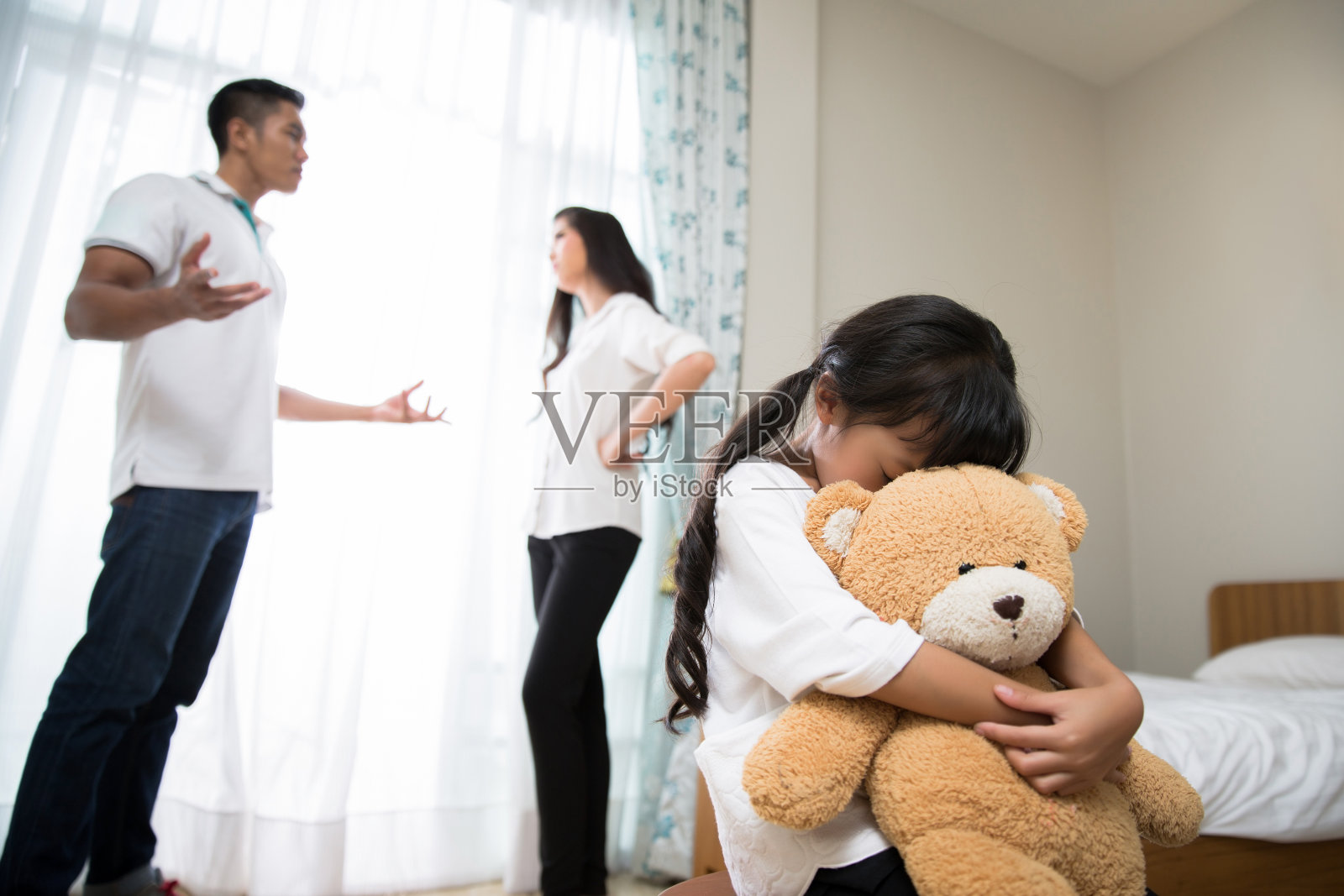 父母吵架女儿感到压力大。她抱着一只泰迪熊哭了起来照片摄影图片