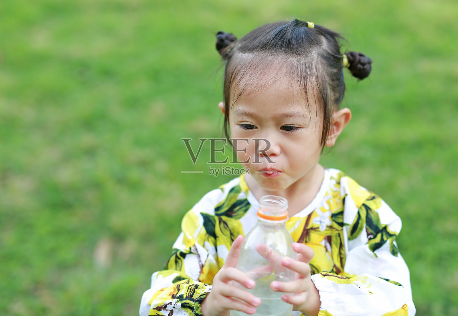 近距离观察小女孩在公园里喝瓶子里的水。肖像户外。照片摄影图片