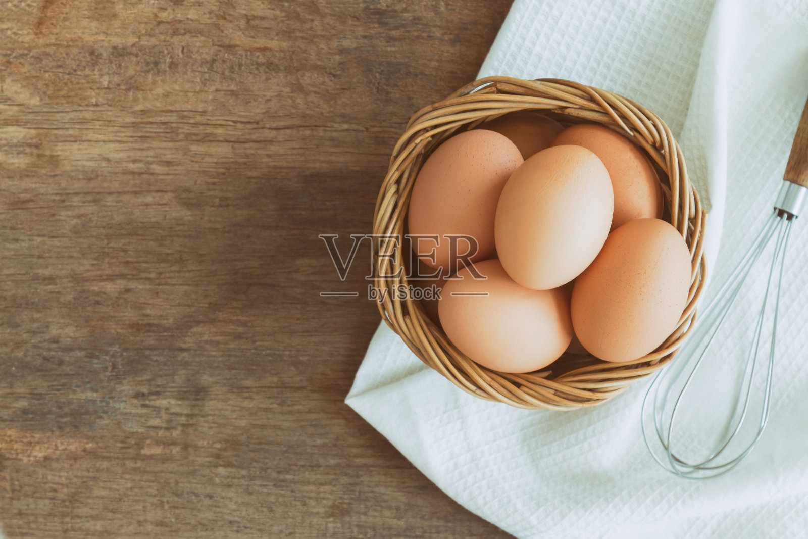 新鲜的鸡蛋放在旧木篮子里，铺上白餐巾。在木桌上准备新鲜的鸡蛋用于烹饪或烘焙。俯视图或平鸡蛋与复制空间的背景或墙纸。照片摄影图片