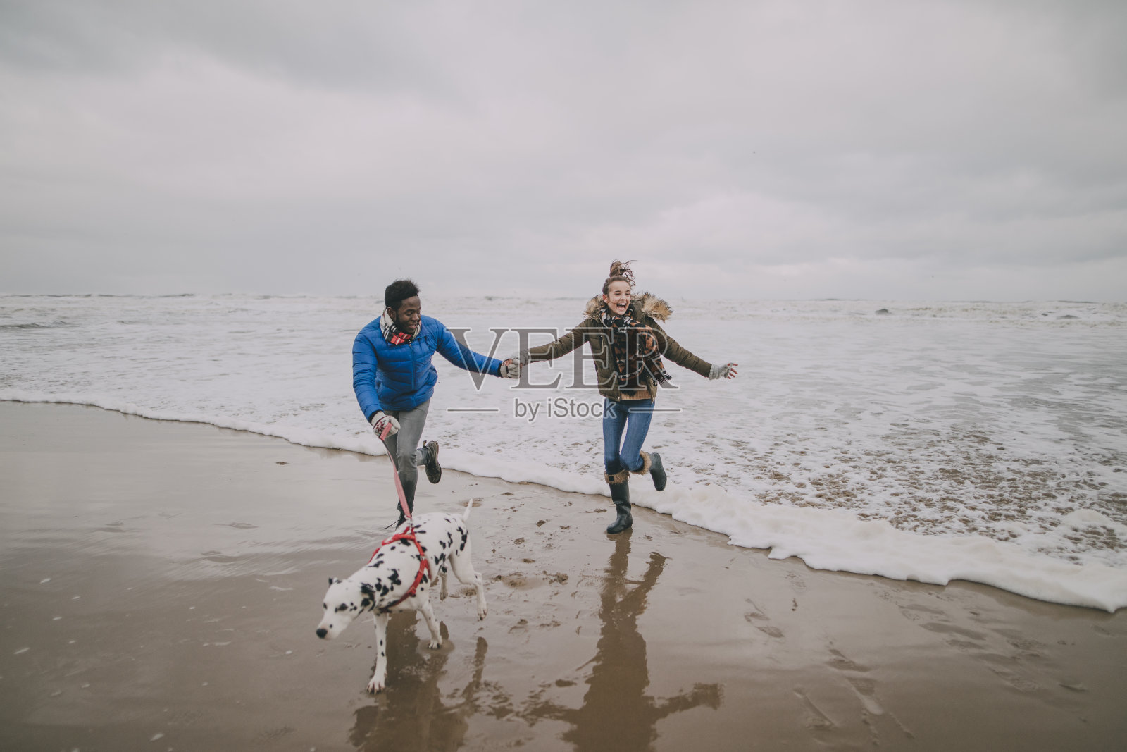 年轻夫妇在冬季海滩上躲避海浪照片摄影图片