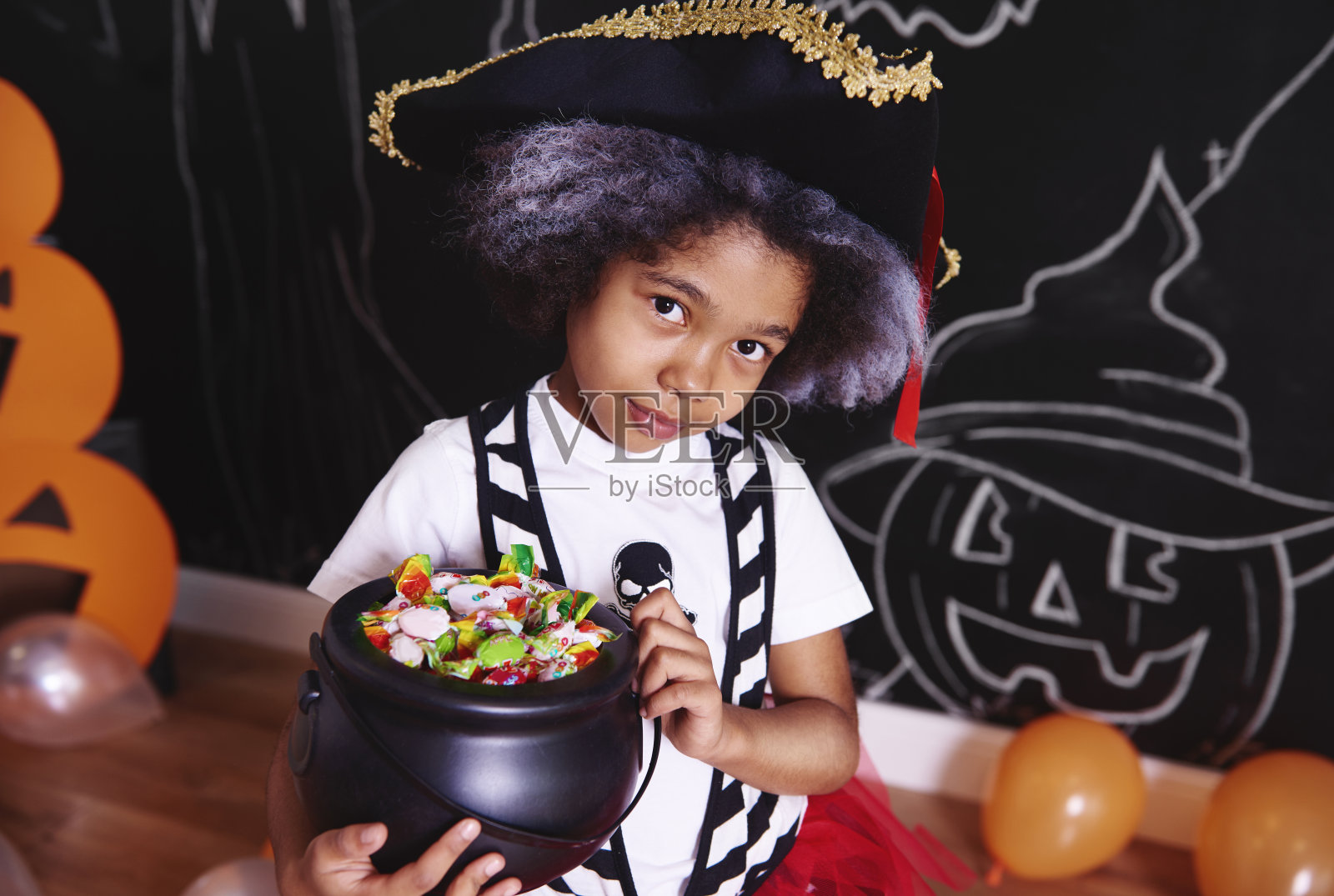 穿着海盗服装的女孩拿着一碗糖果照片摄影图片