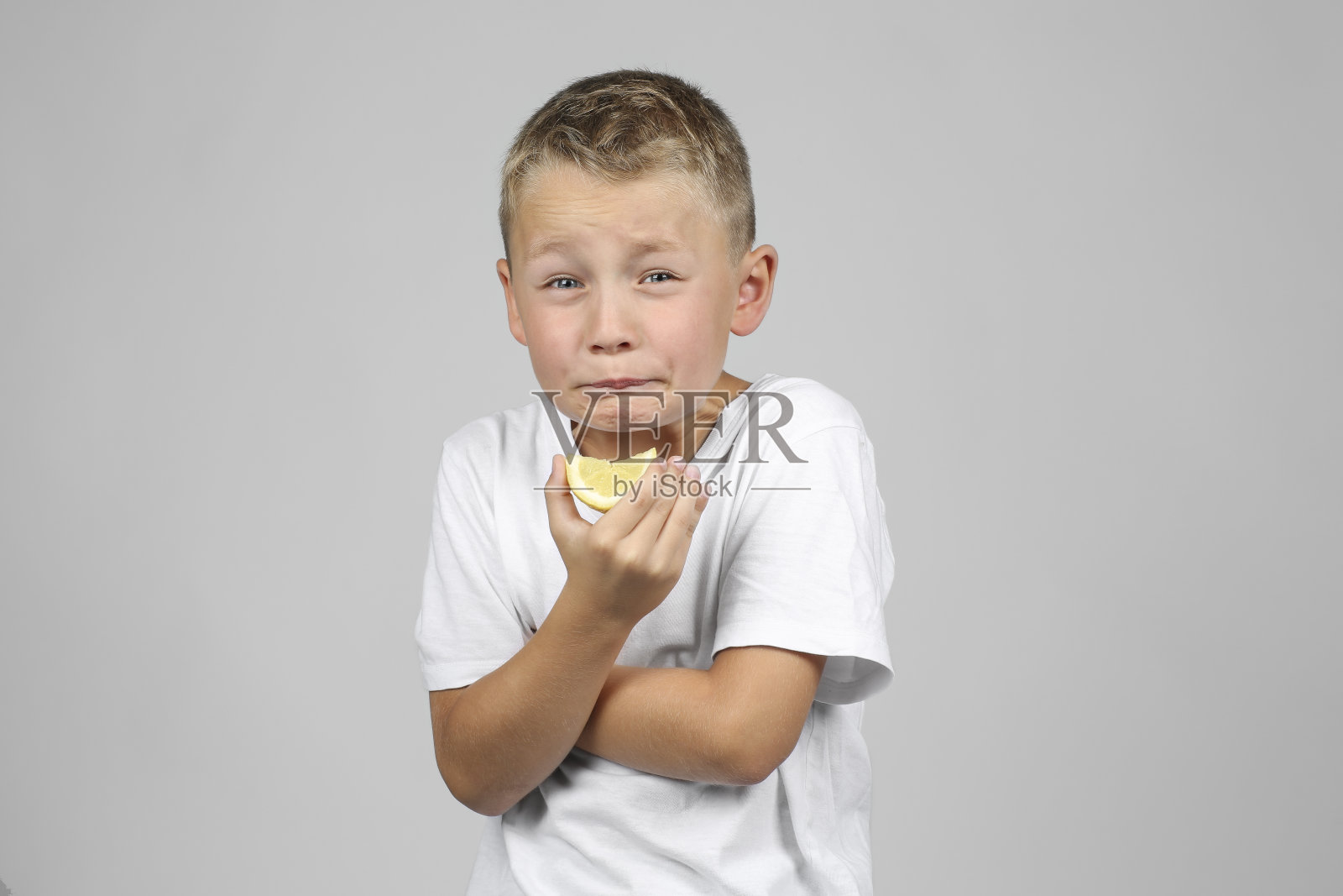 金发小男孩在咬柠檬照片摄影图片