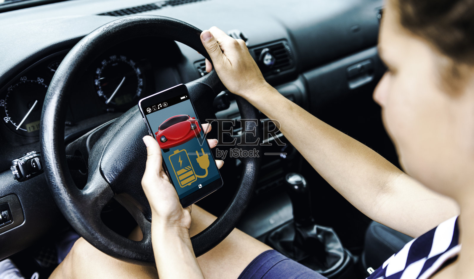 一名女子在开车前通过手机应用程序查看她的汽车电池寿命照片摄影图片
