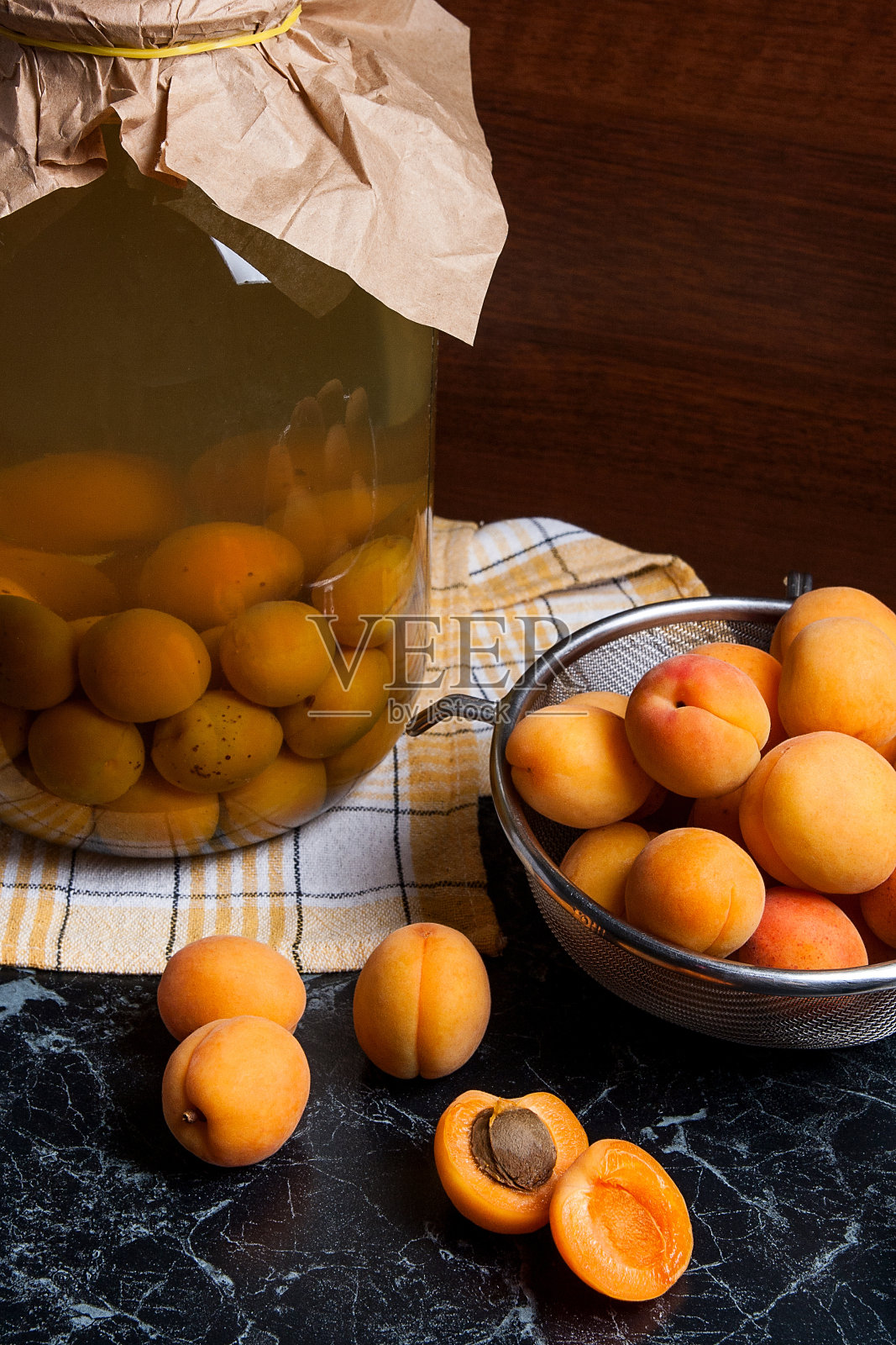 有机收获的杏子在钢滤器和杏罐头蜜饯照片摄影图片