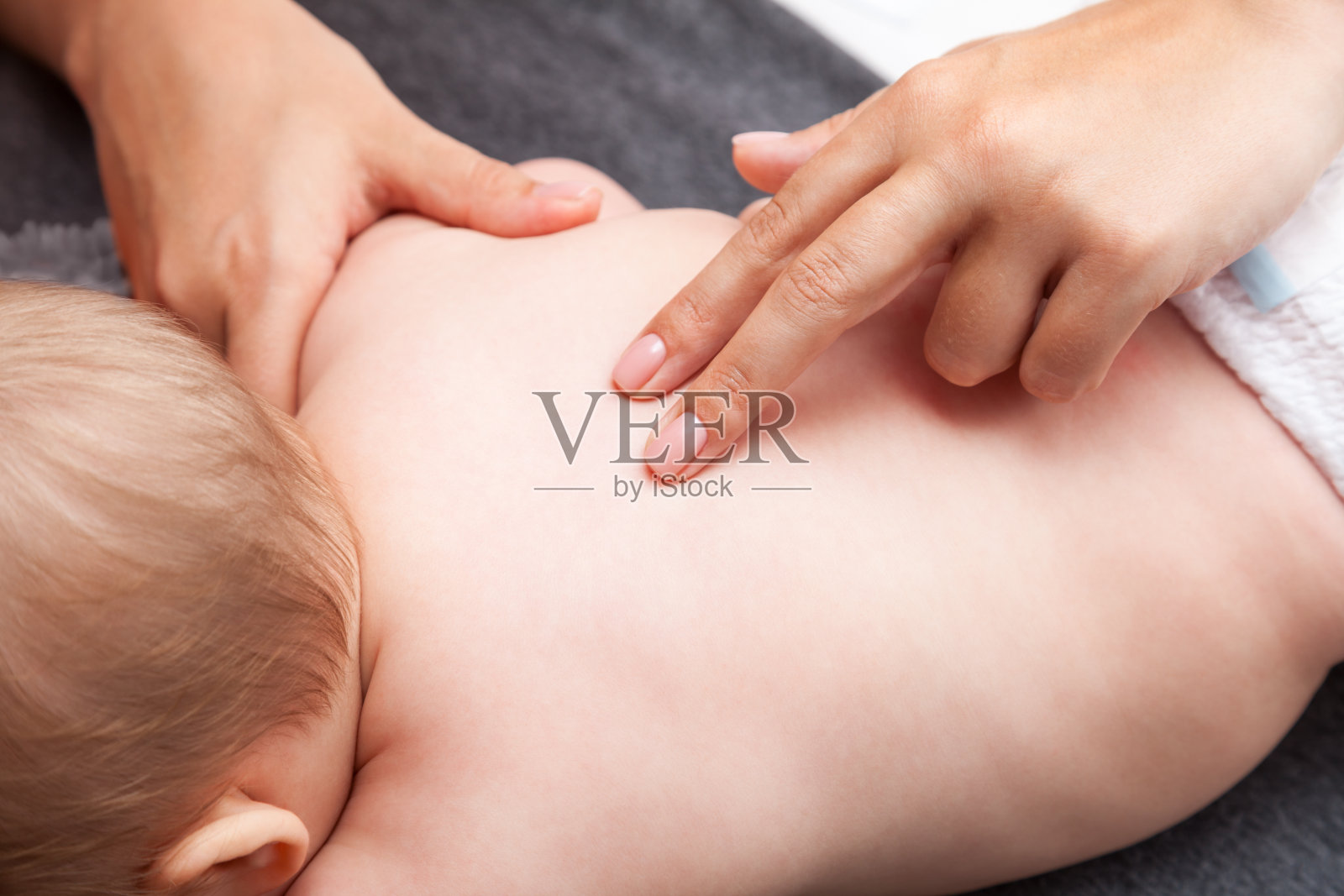 小婴儿正在接受脊椎按摩治疗她的背部照片摄影图片