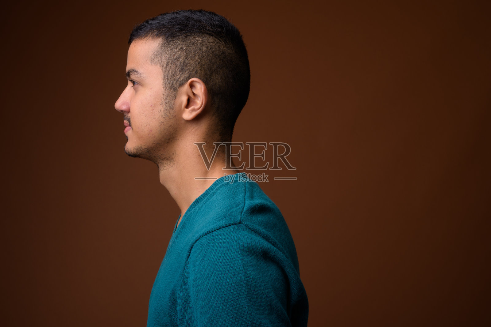 工作室拍摄的年轻多民族亚洲男子穿着长袖蓝色衬衫，以有色背景照片摄影图片
