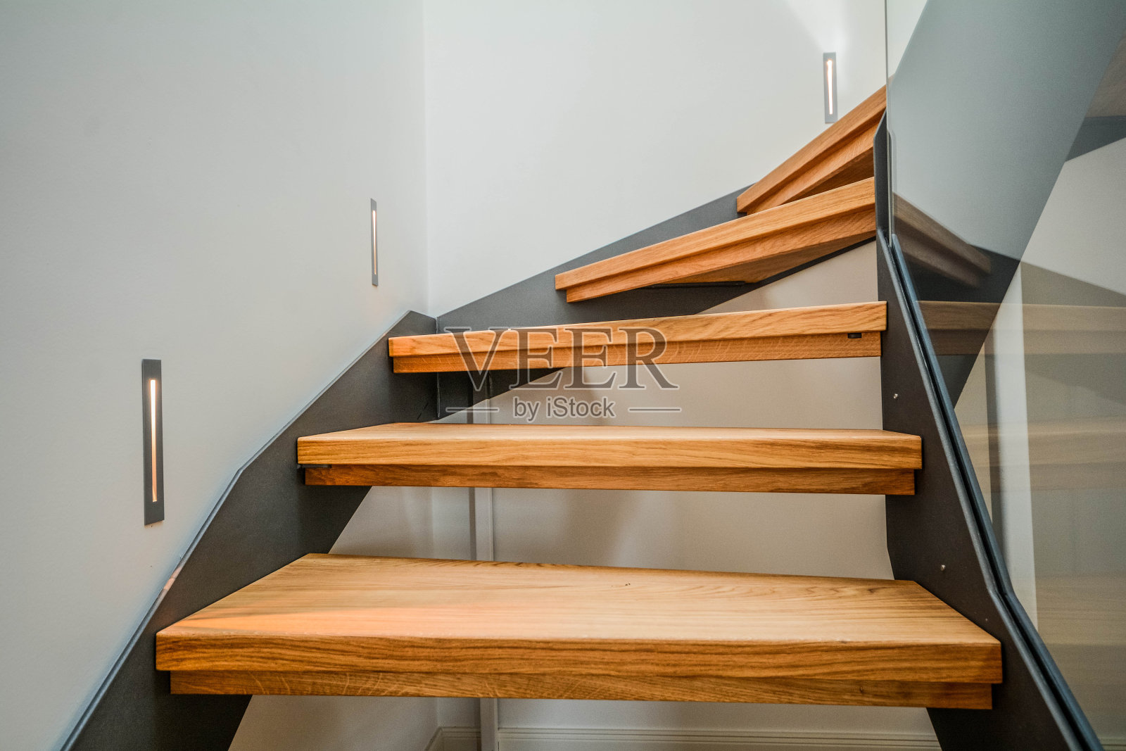 在一幢住宅楼的新公寓里，现代钢制楼梯和木制台阶照片摄影图片