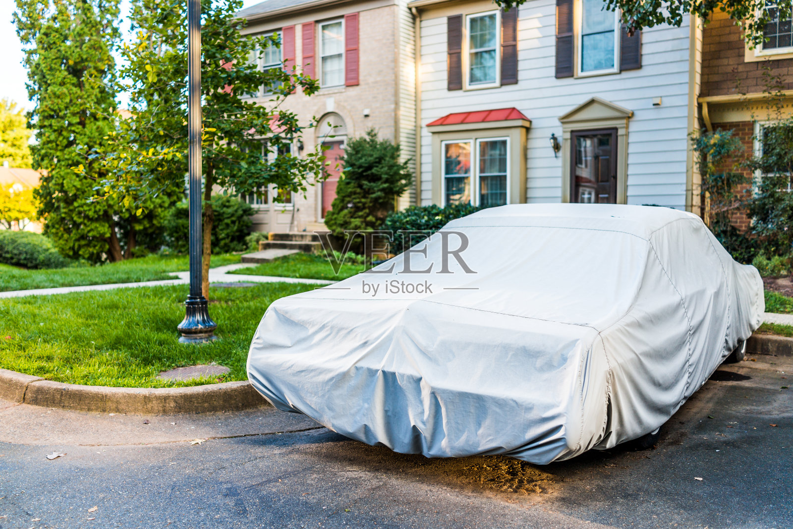 老式汽车覆盖的保护盖由联排别墅停车场潮湿的天气照片摄影图片