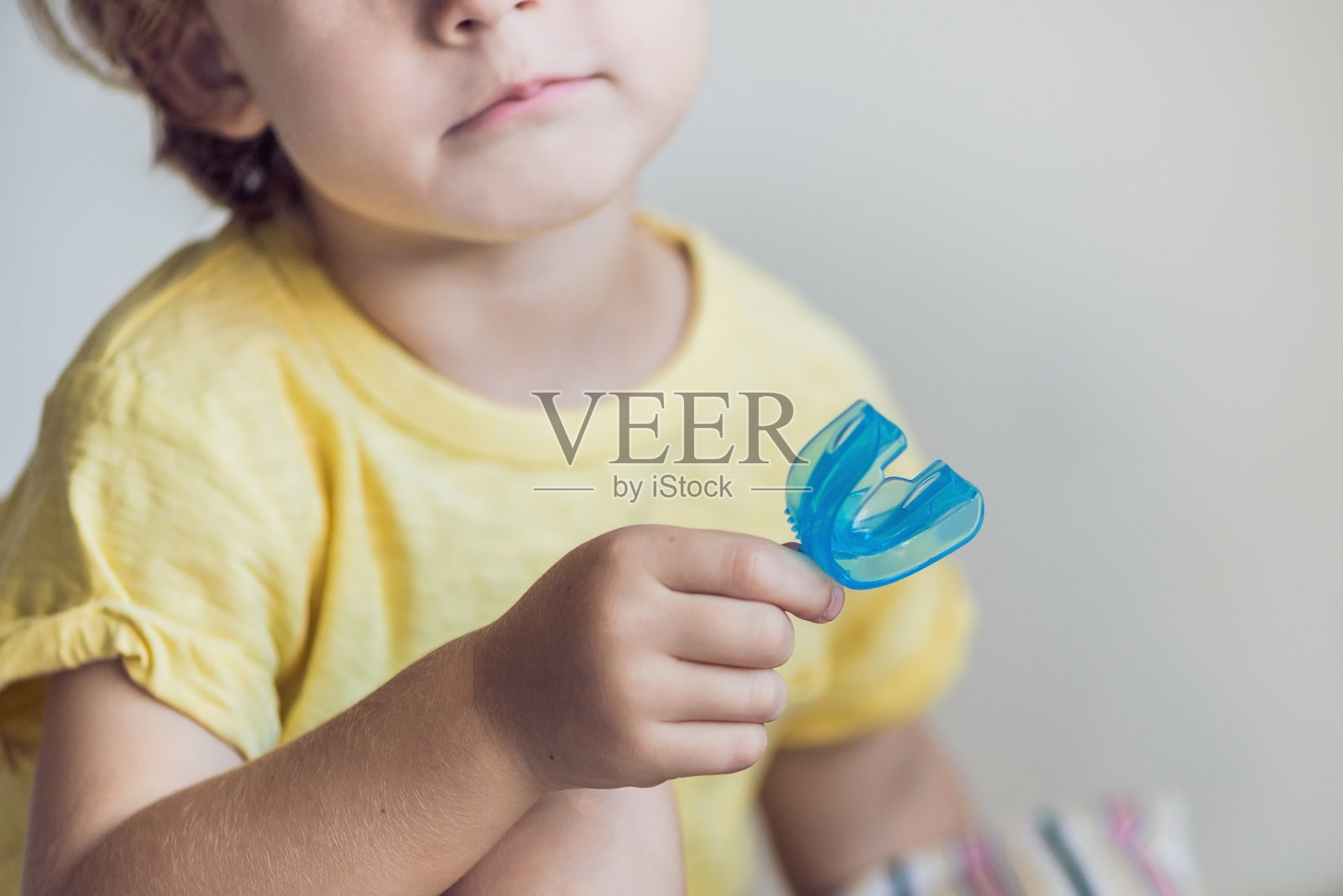 三岁男孩展示肌肉功能训练器。帮助平衡生长的牙齿和正确的咬合，养成口腔呼吸习惯。纠正舌头的位置照片摄影图片