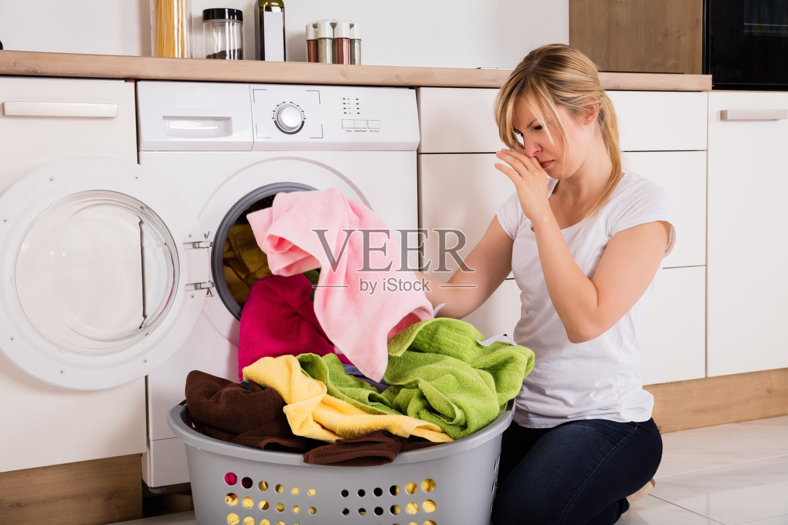 一个女人从洗衣机里取出难闻的衣服照片摄影图片