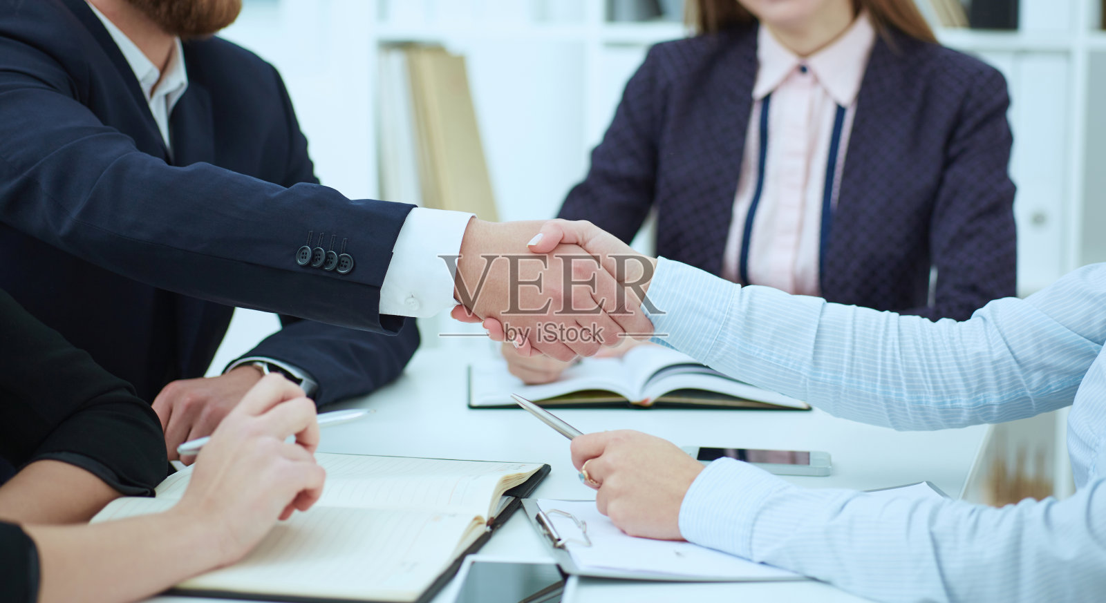 男性和女性在办公室握手。严肃的商业和伙伴关系理念。合伙人达成交易，以握手封缄。照片摄影图片