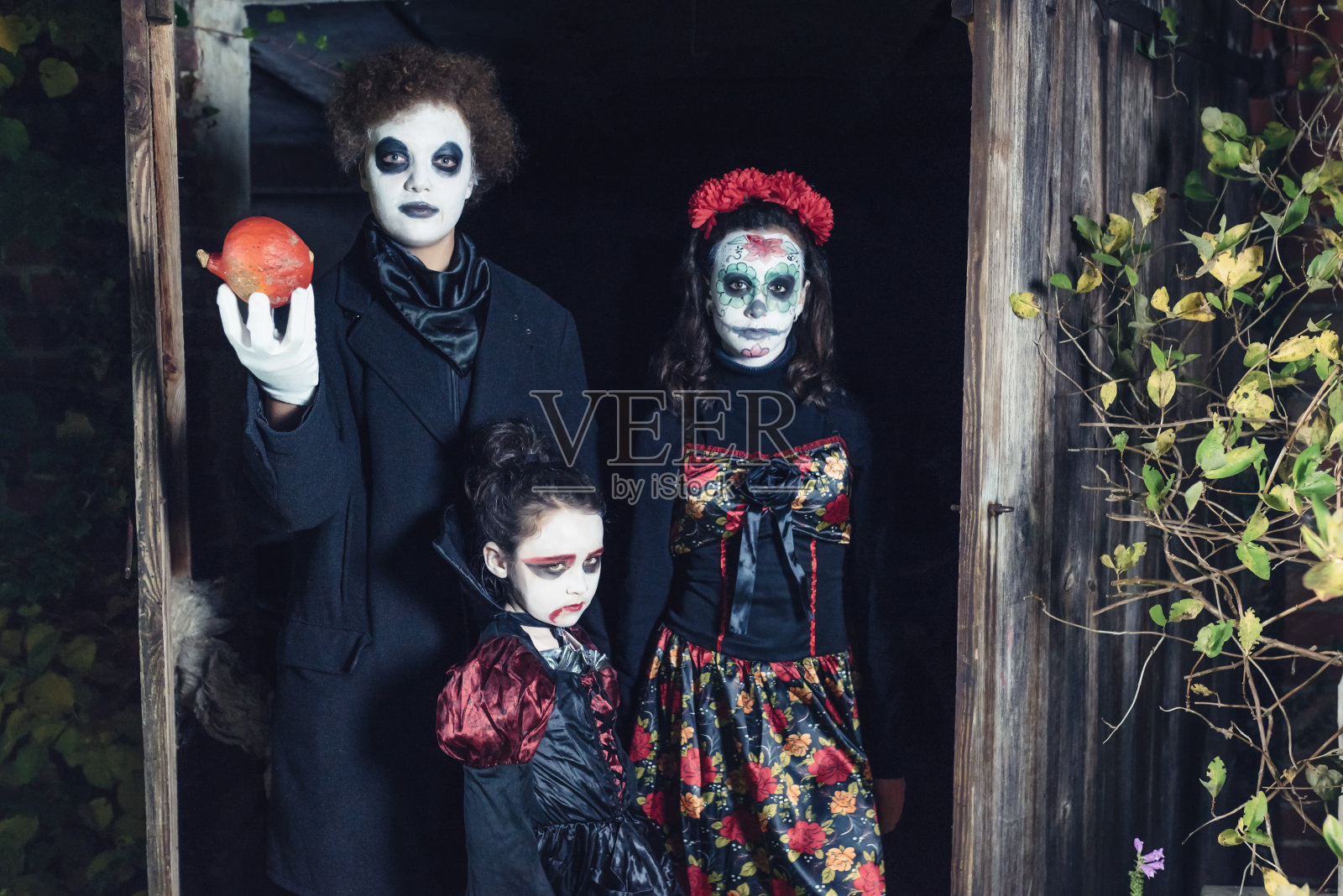 三个孩子穿着诡异的万圣节服装在旧谷仓里照片摄影图片