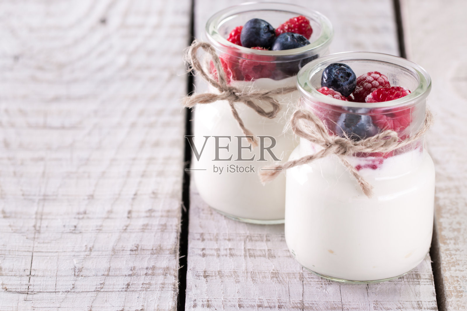 新鲜的混合浆果和酸奶与农场的新鲜草莓，和蓝莓在一张木桌上，这是健康的早餐照片摄影图片