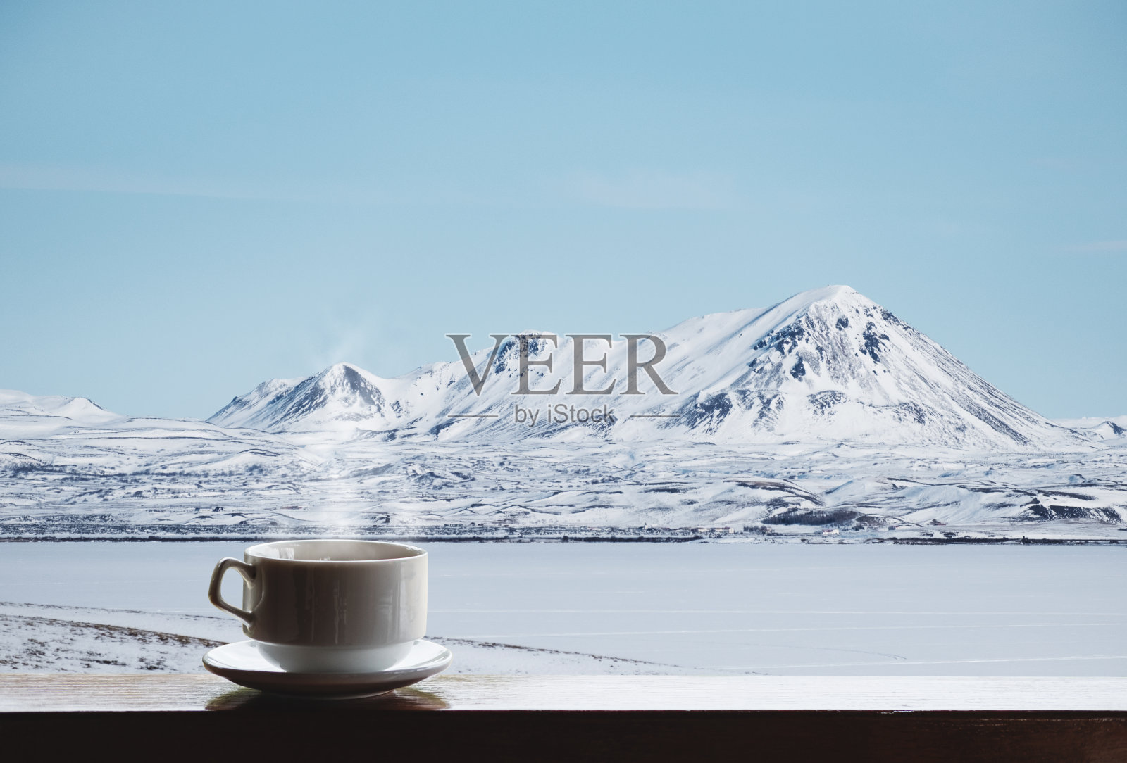 早晨，木桌上一杯带蒸汽的热饮，欣赏冬日美景照片摄影图片
