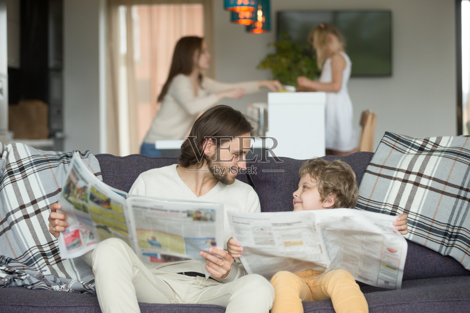 祝爸爸和小儿子在沙发上一起看报纸照片摄影图片