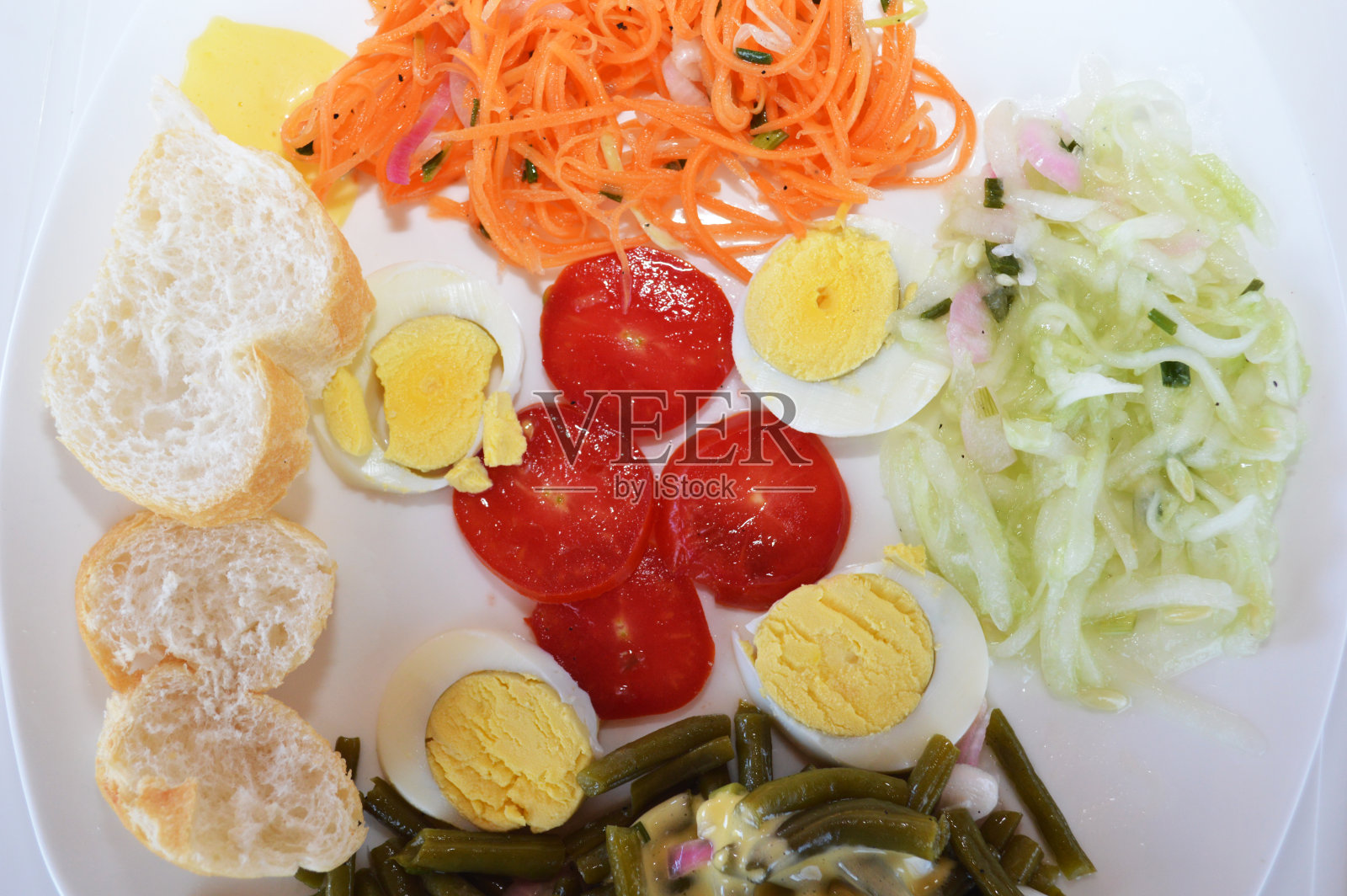 冷盘由法国面包片、番茄沙拉、胡萝卜沙拉、黄瓜沙拉、绿豆沙拉、蛋黄酱和煮熟的鸡蛋组成，切成片。照片摄影图片