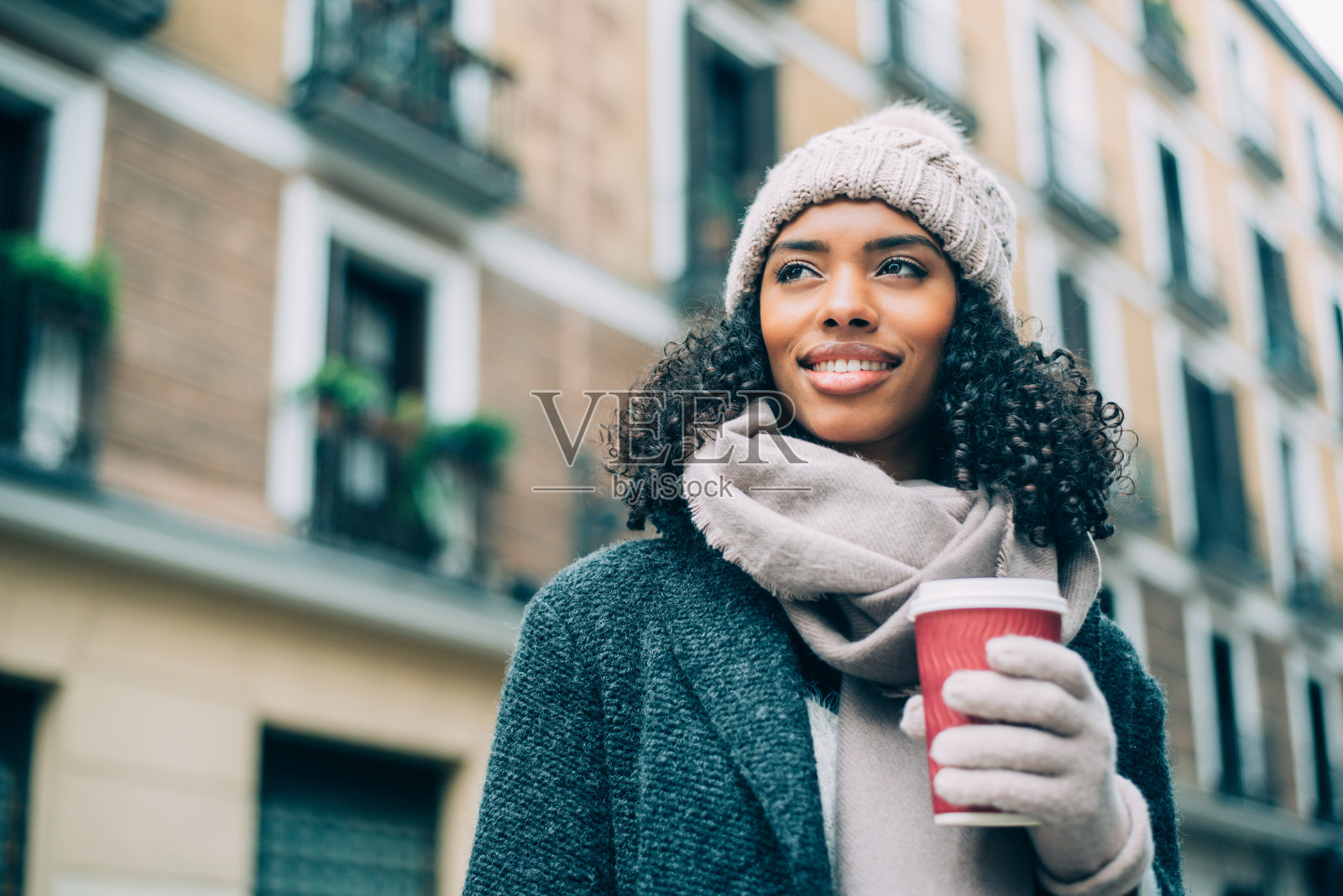 年轻的黑人妇女喝着咖啡在马德里的街道上漫步照片摄影图片