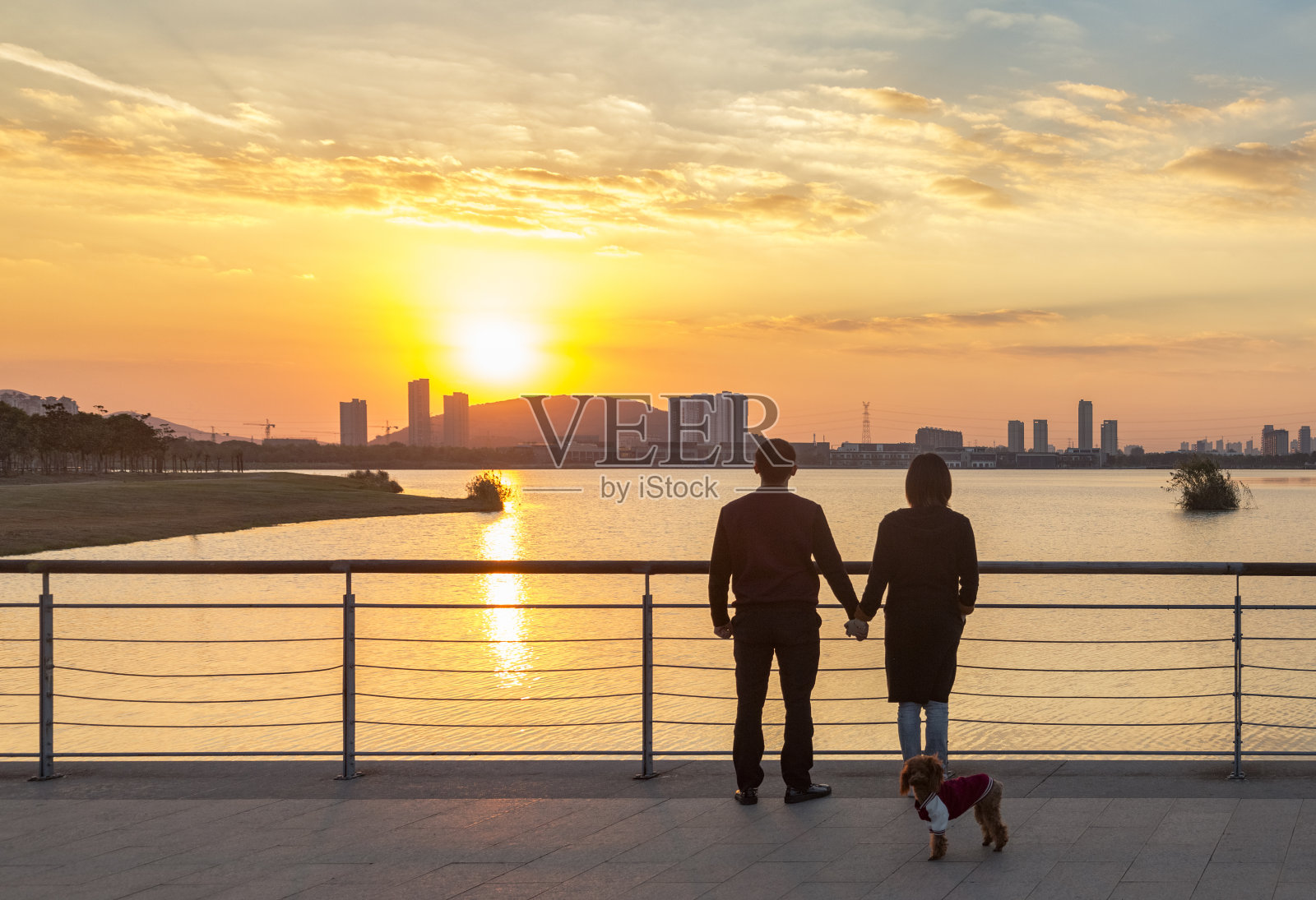年轻夫妇和他们的小狗狗看风景在日落照片摄影图片