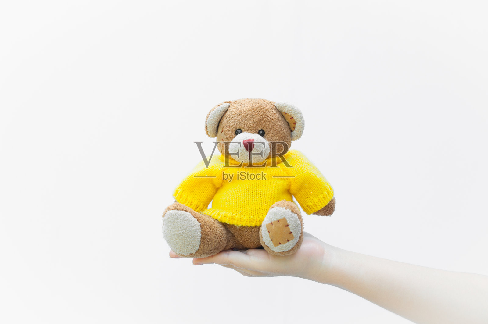 女人抱着并保护着给一个棕色的泰迪熊玩具穿黄色的衬衫坐在白色的上面照片摄影图片