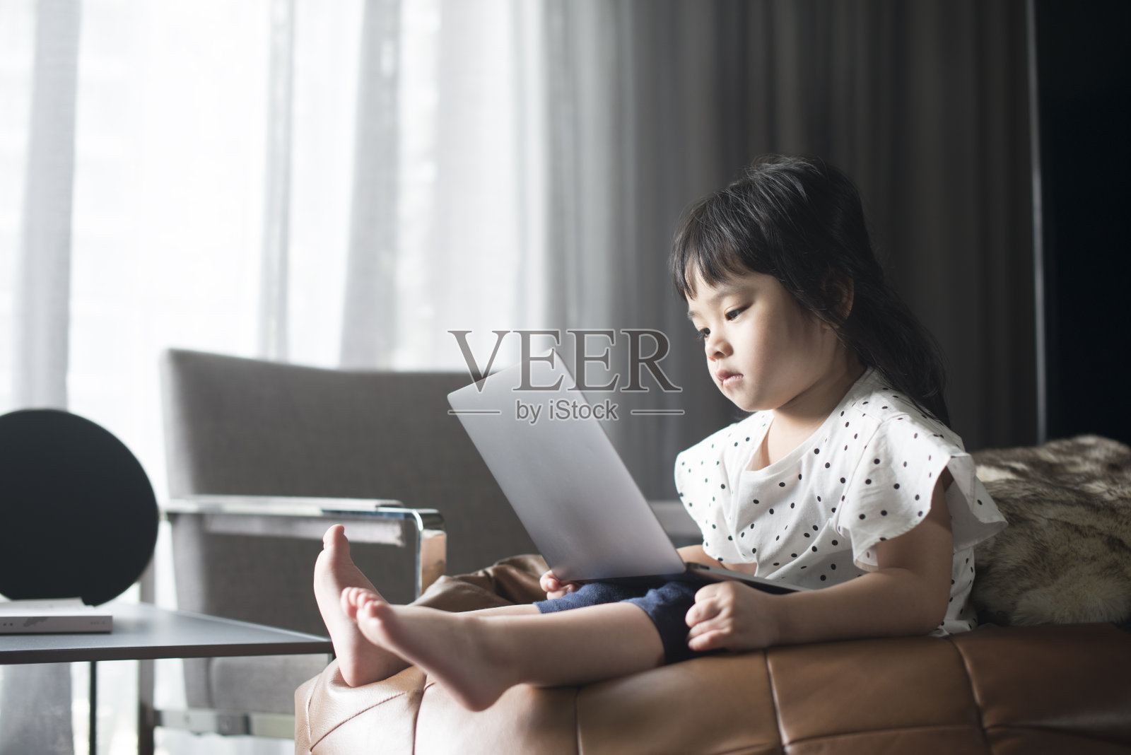 年轻的亚洲女孩在家里看电脑。照片摄影图片