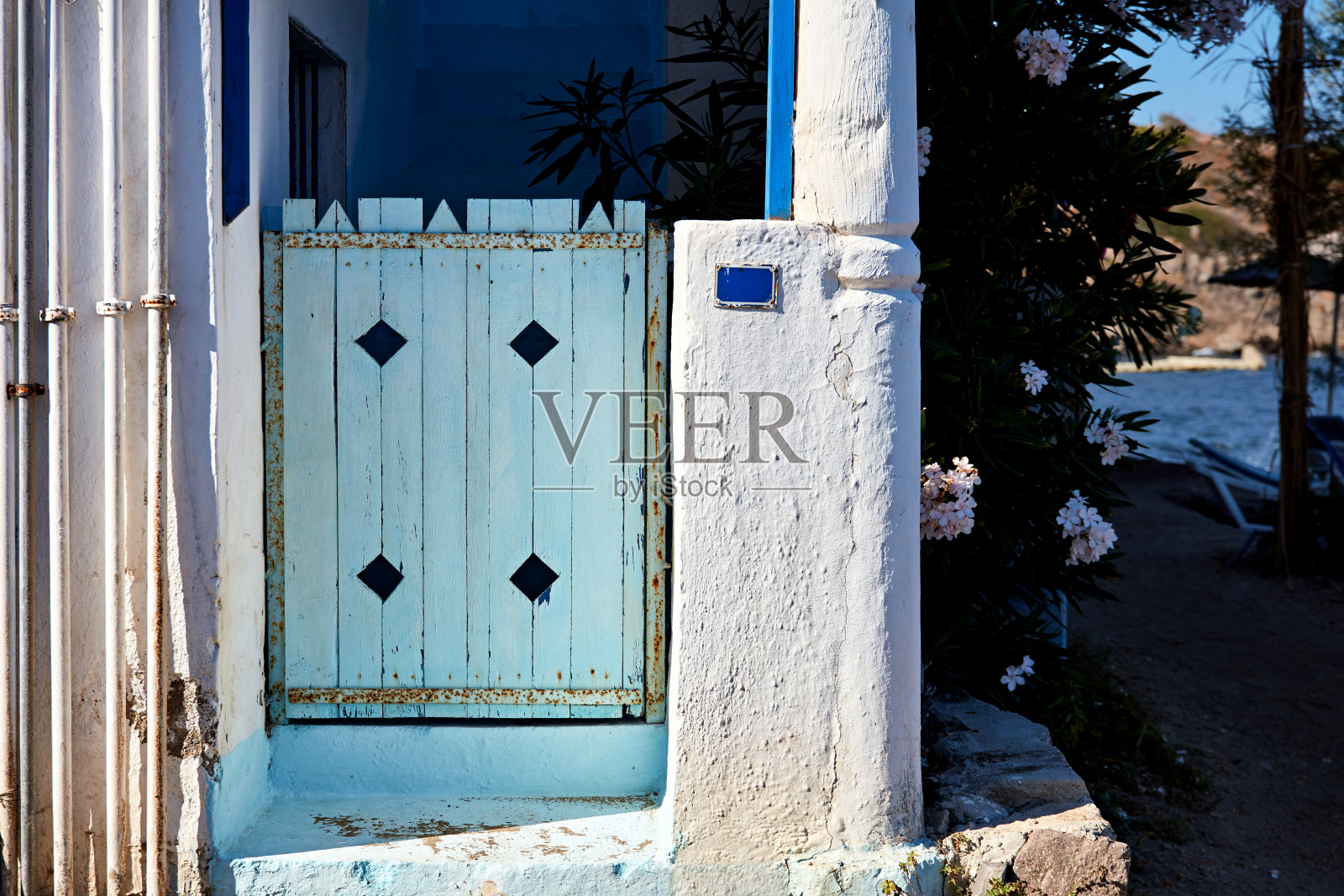 一座白色爱琴海房屋的蓝色木质庭院门照片摄影图片