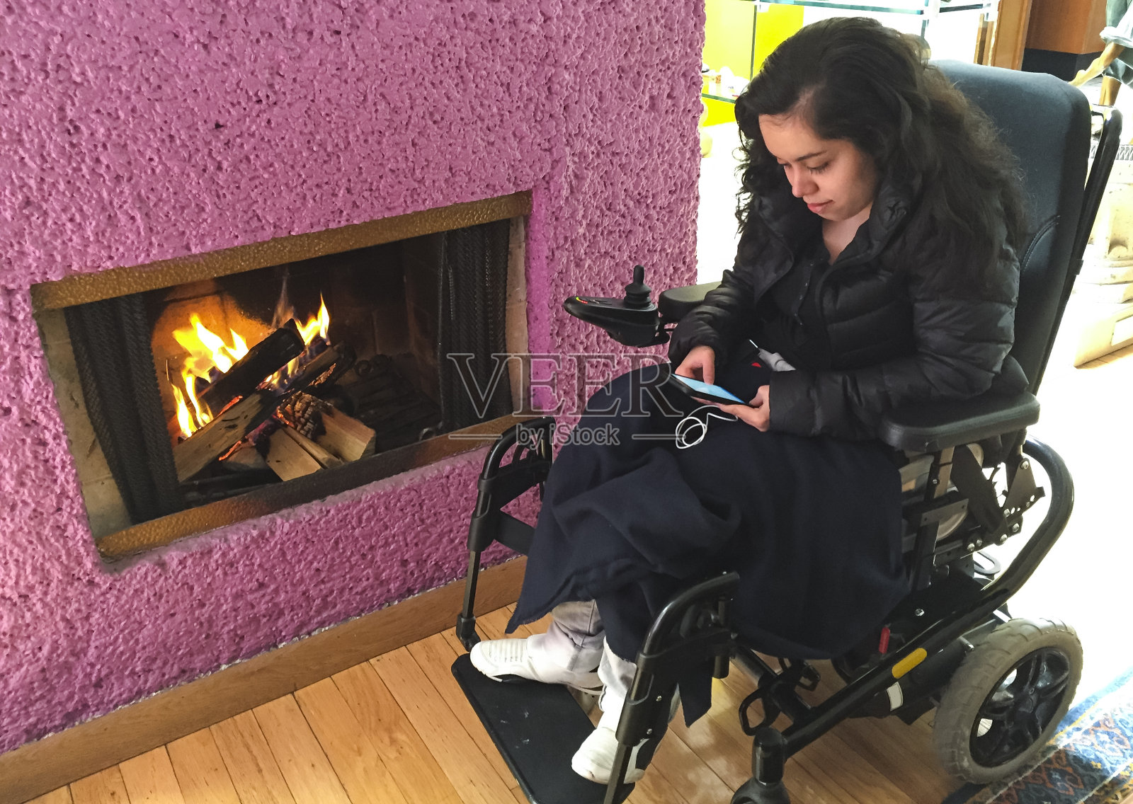 残疾女孩在壁炉边，用着她的智能手机照片摄影图片