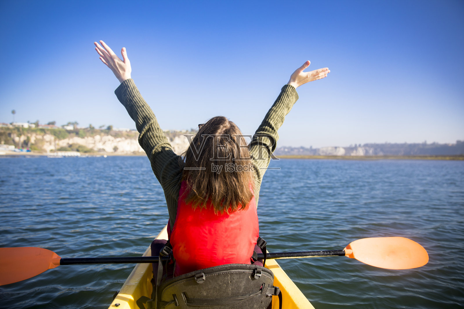 年轻女子举起手臂在海湾划皮艇照片摄影图片