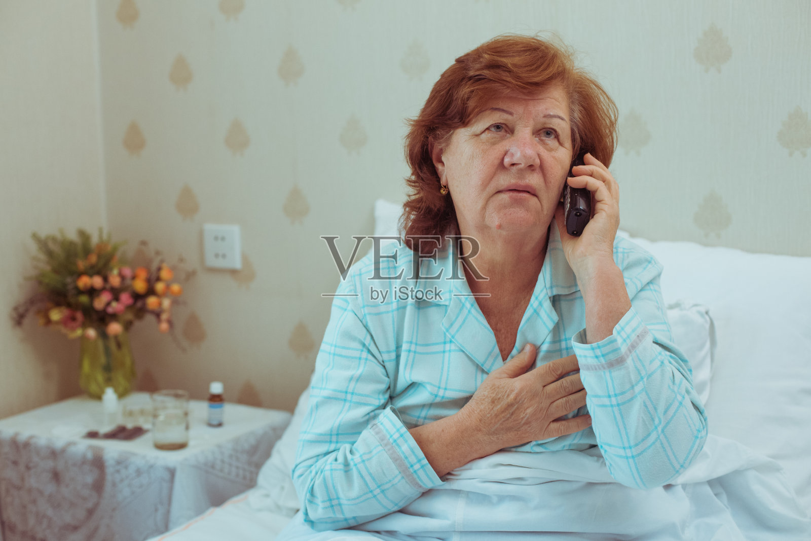 生病的老妇人在叫她的医生。照片摄影图片