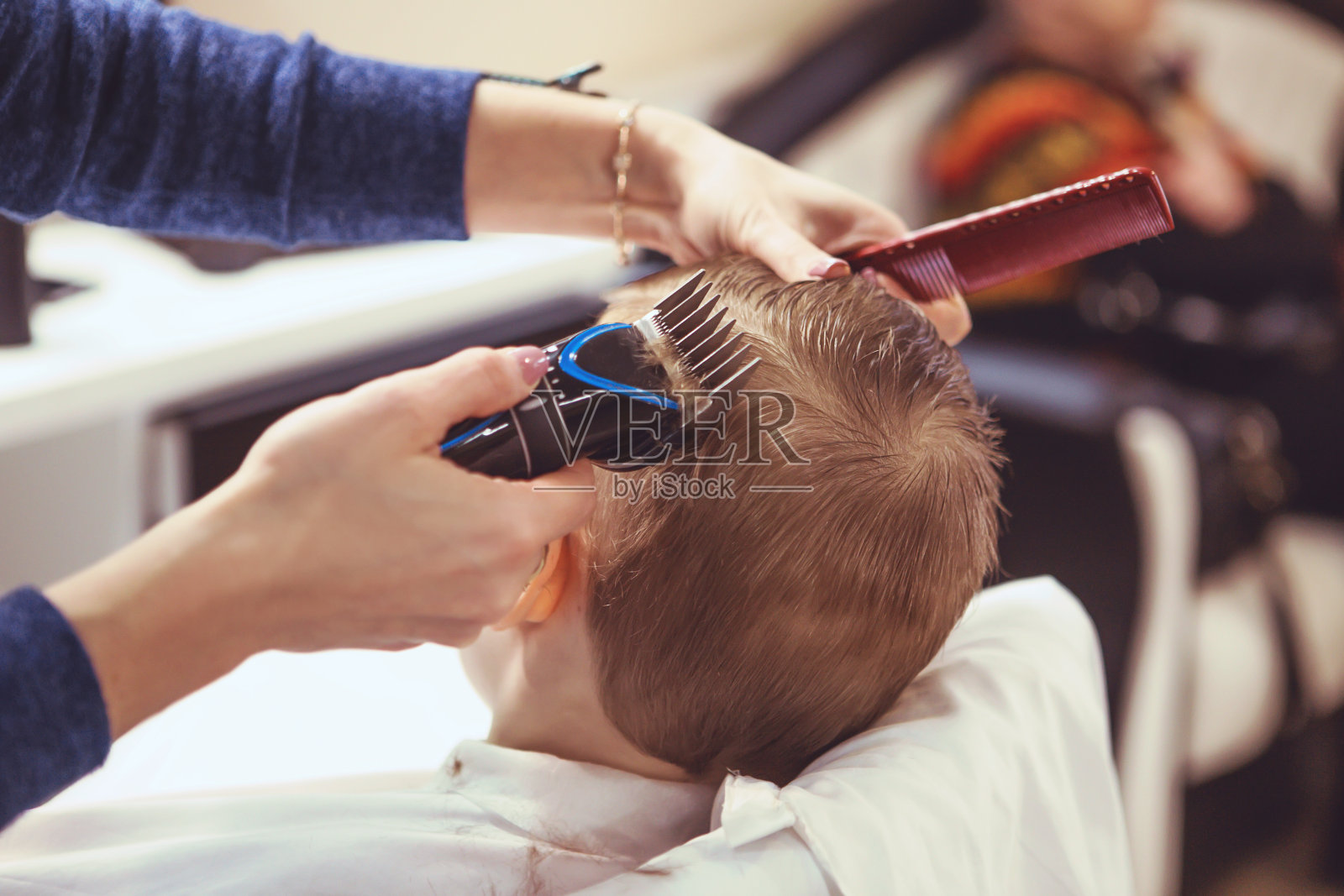 理发师的手给小男孩做发型，特写。男孩的时尚发型。照片摄影图片