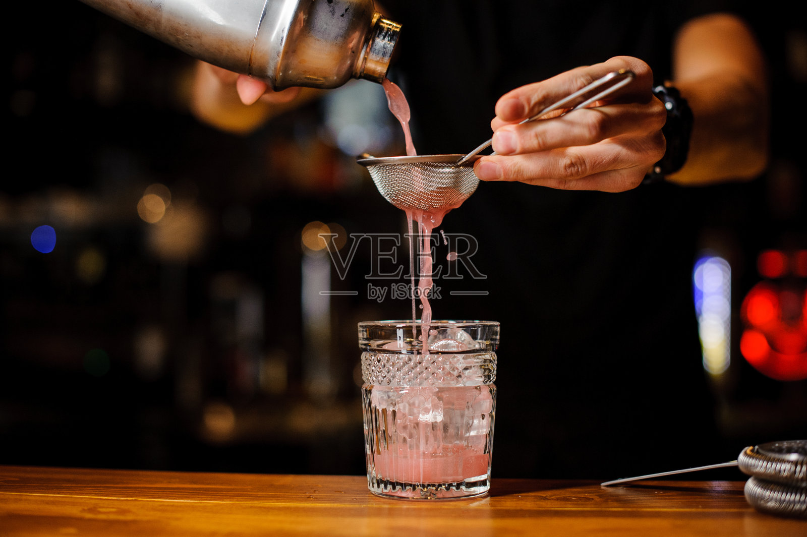 酒保在酒吧用手倒着粉红色的鸡尾酒饮料照片摄影图片