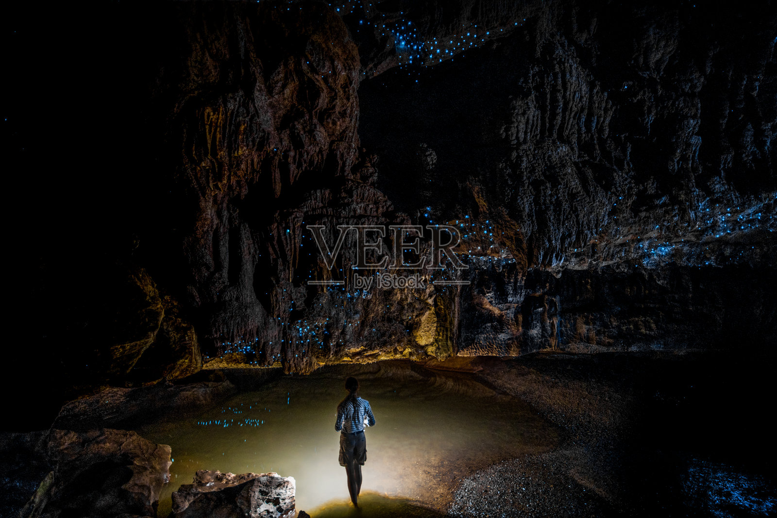 在新西兰的外普洞穴，站在萤火虫天空下的女孩照片摄影图片