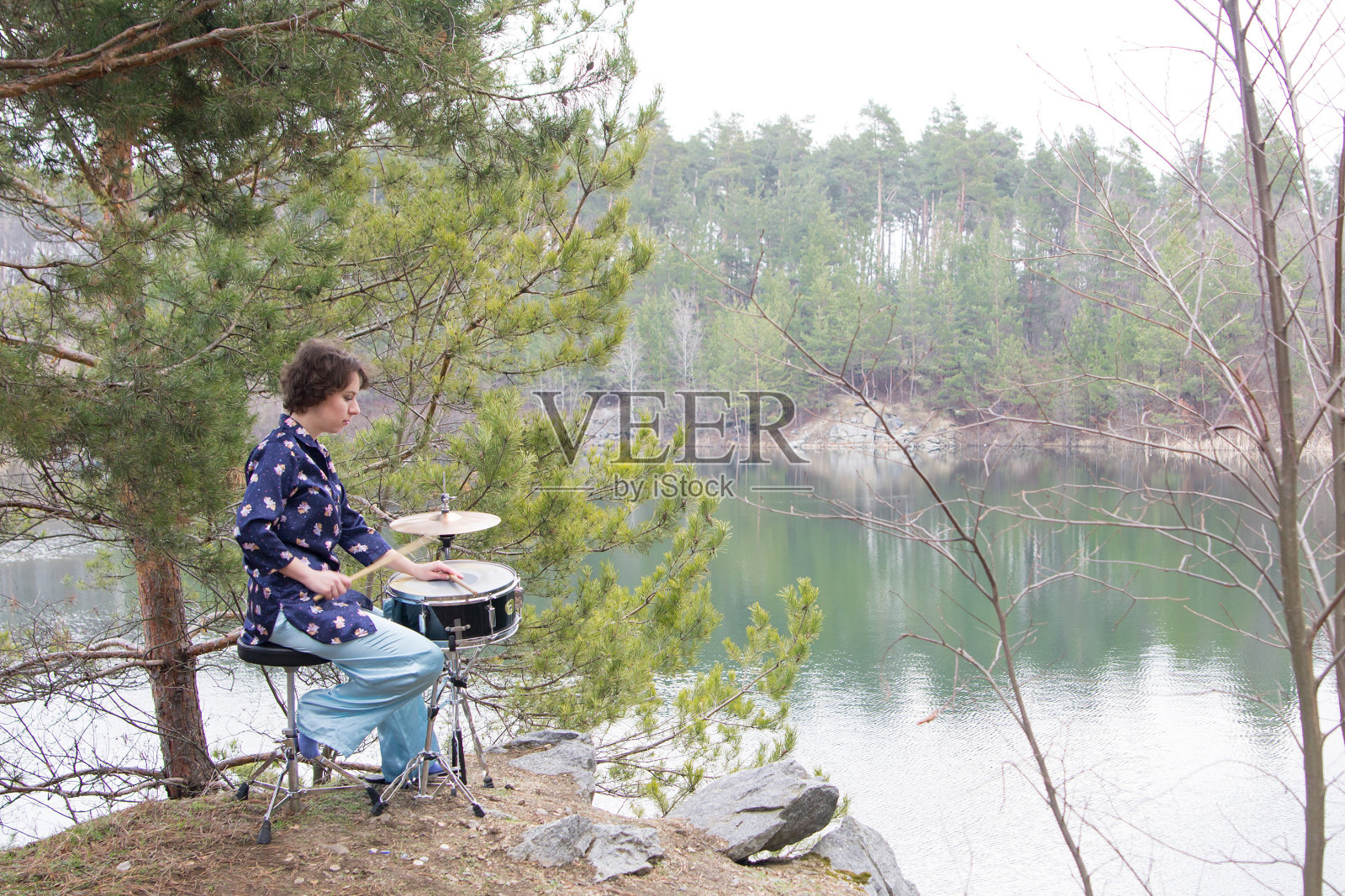 女音乐家在湖边的森林里打架子鼓照片摄影图片