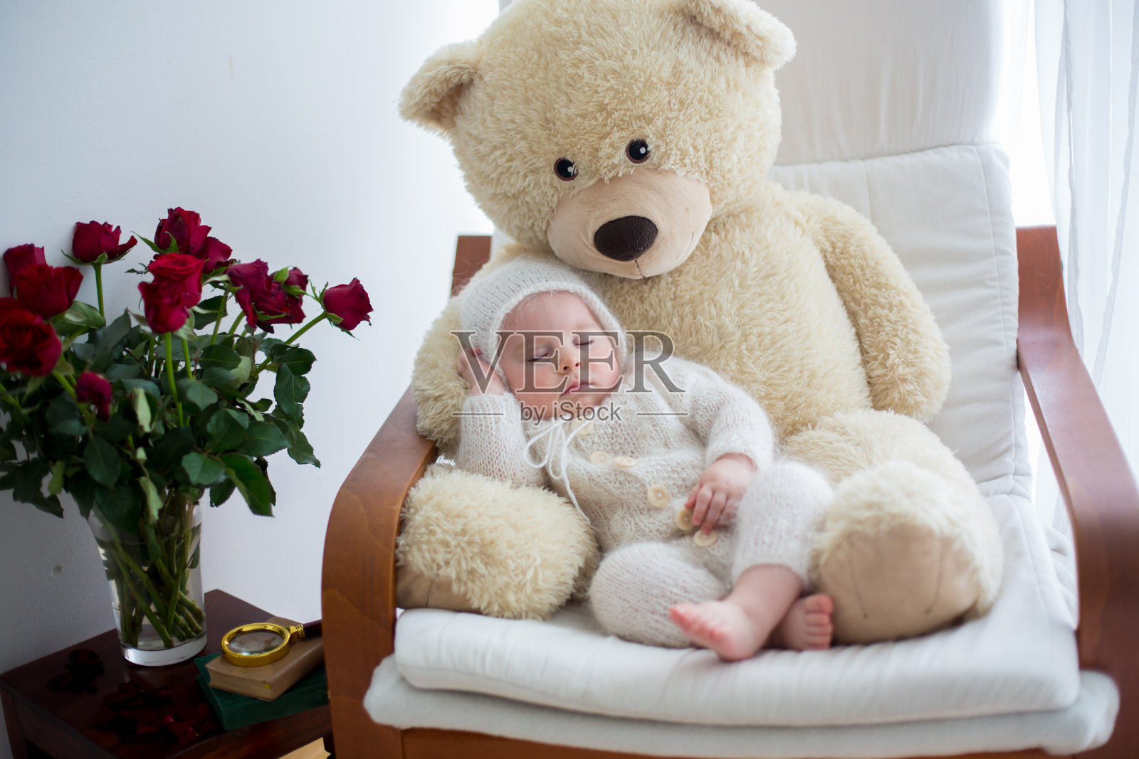 可爱的小男孩，和巨大的泰迪熊睡在大扶手椅上照片摄影图片